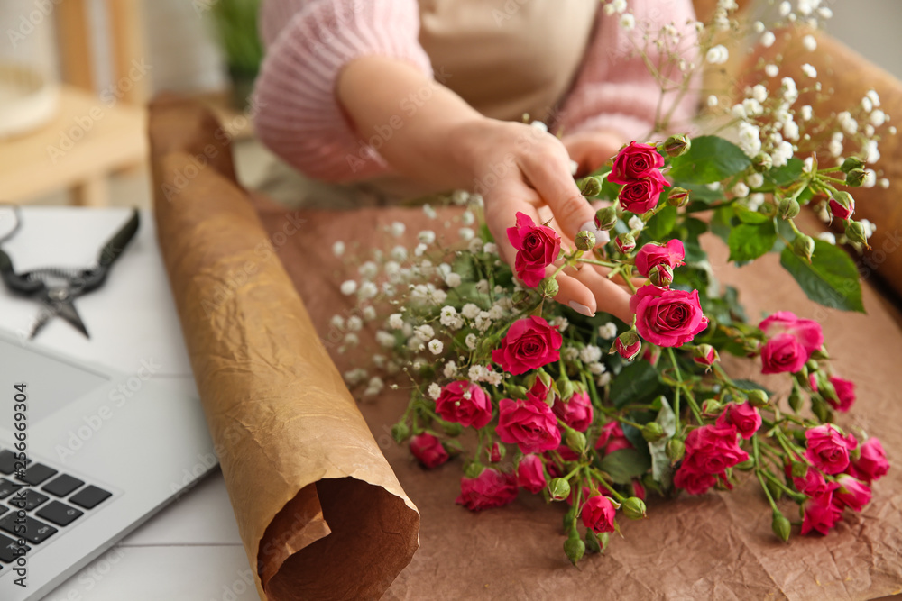 Beautiful female florist working at table in shop, closeup