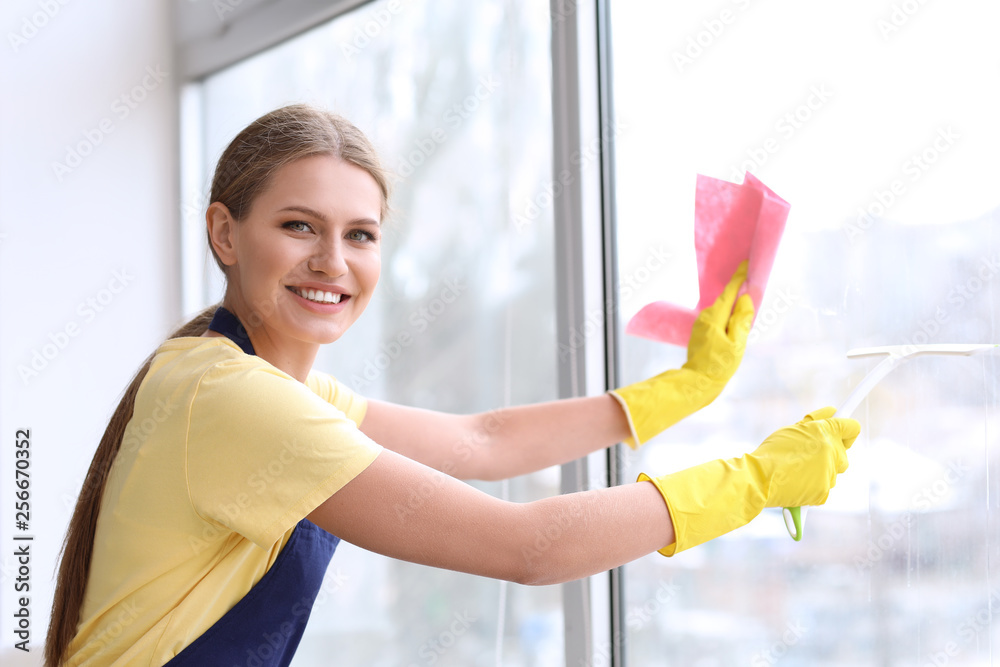 Beautiful woman cleaning window at home