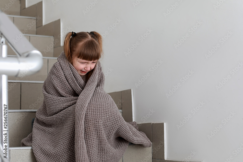 Portrait of crying little girl sitting on stairs