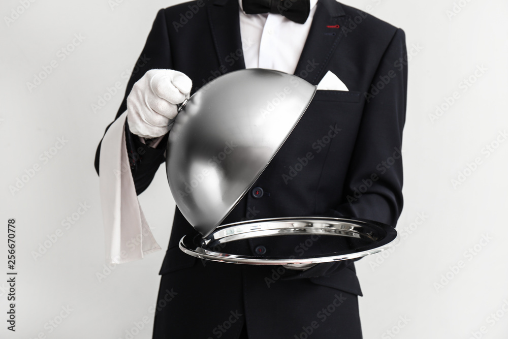 Waiter with tray and cloche on light background