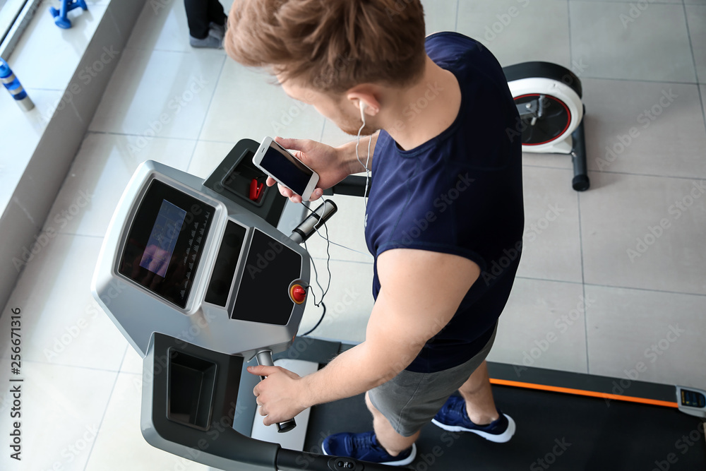 Sporty young man training on treadmill in gym