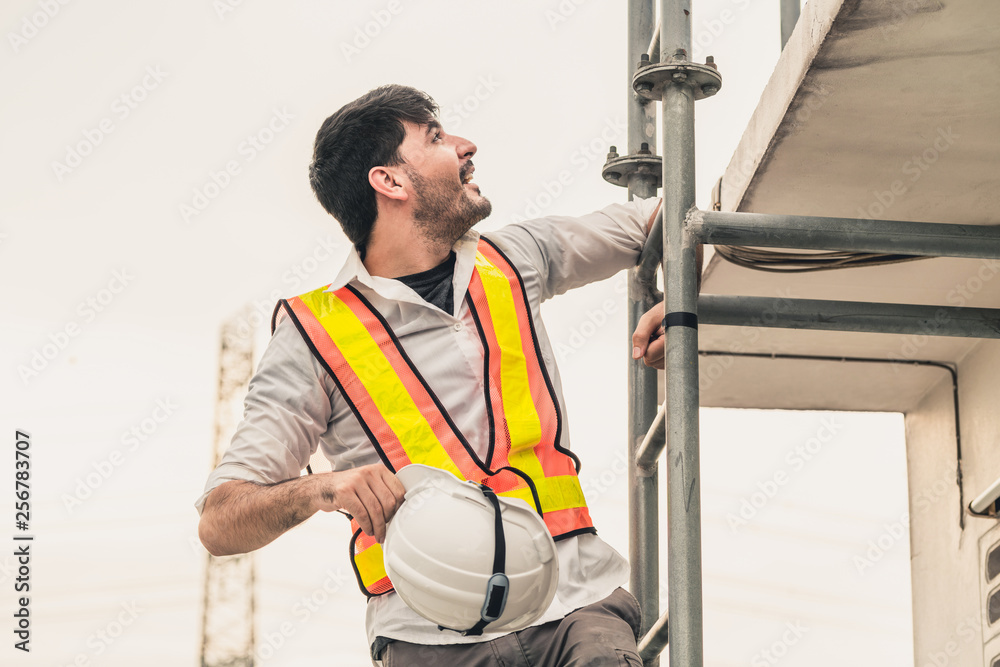 Young man construction worker or engineer climb ladder on the building top. Engineering project conc