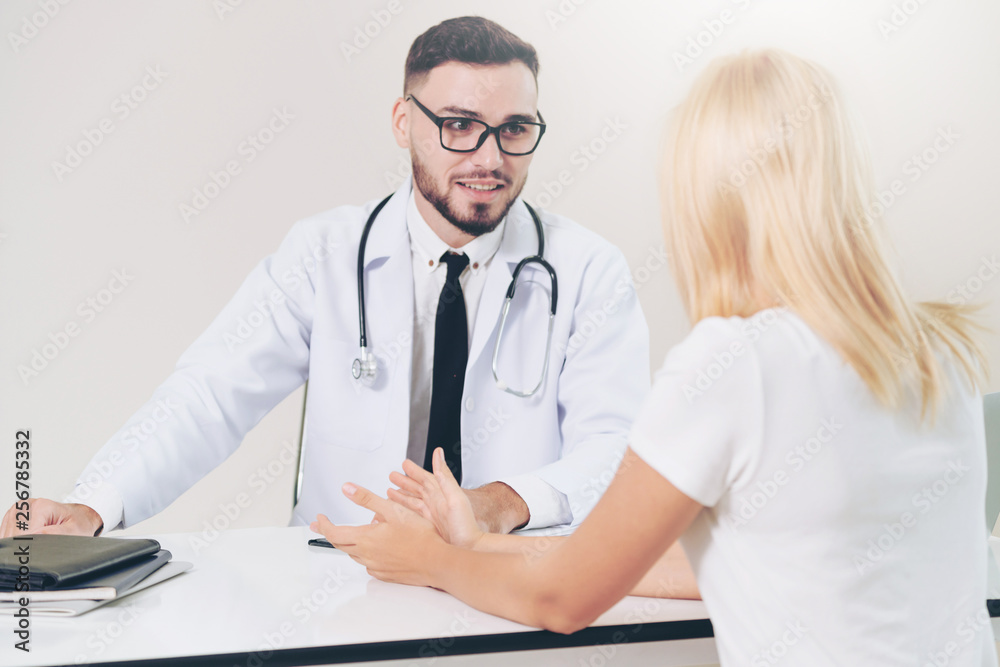 Male doctor is talking to female patient in hospital office. Healthcare and medical service.