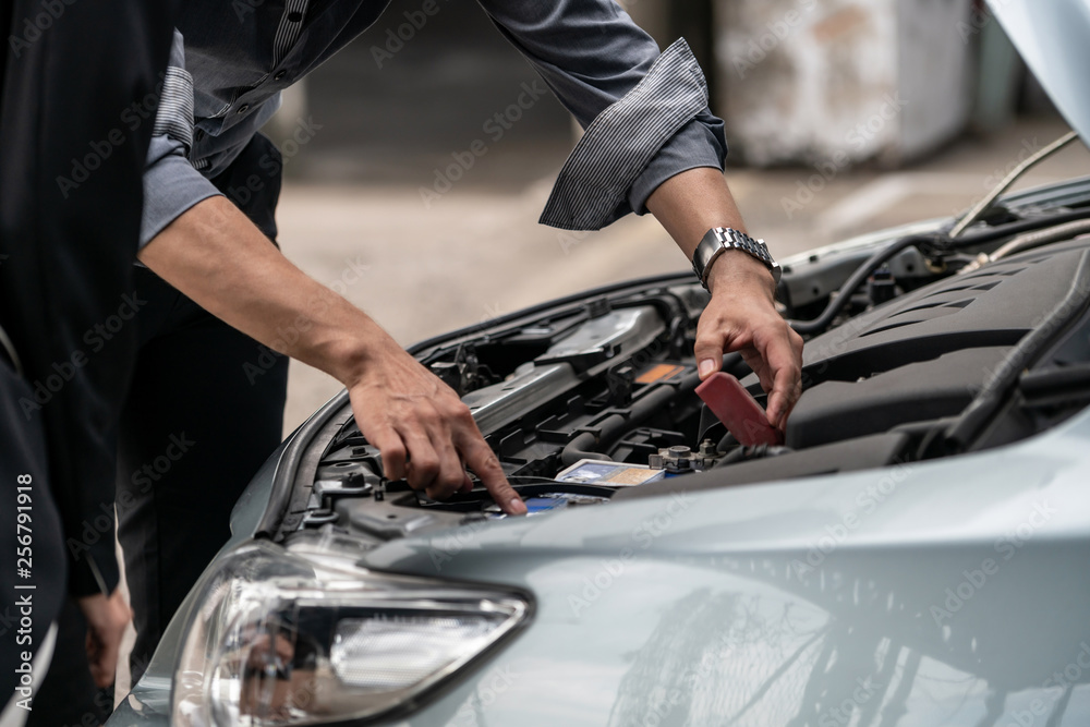 Man help woman fix the car problem. He pop up the car hood to repair the damaged part.