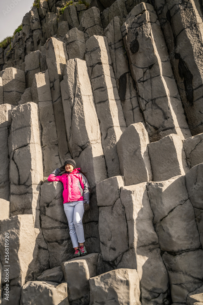 Traveler travel to unique volcanic rock formation on Iceland black sand beach located near the villa