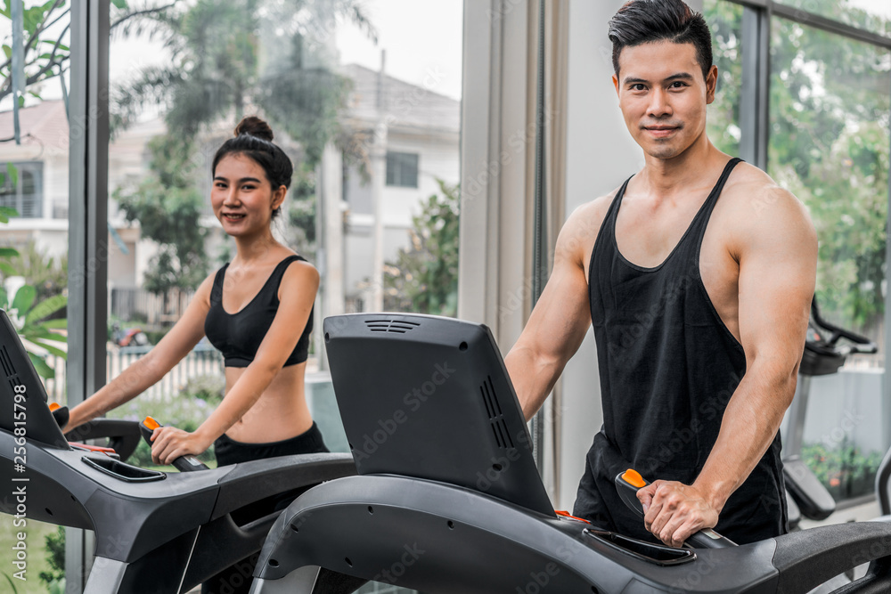 Sporty runner running on treadmill in fitness gym. Healthy lifestyle concept.