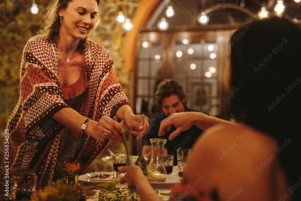 在晚宴上为朋友提供食物的女人