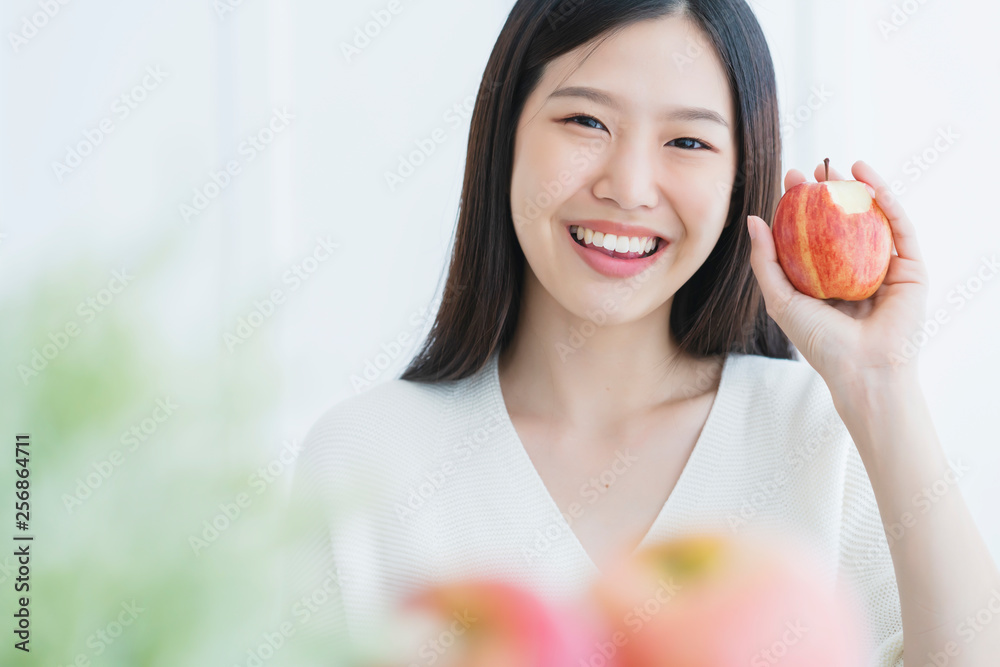 健康美丽迷人的黑色长发女人幸福微笑用额头握住红苹果