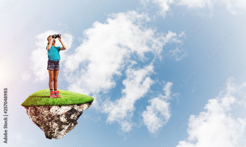 Concept of careless happy childhood with girl looking in binoculars