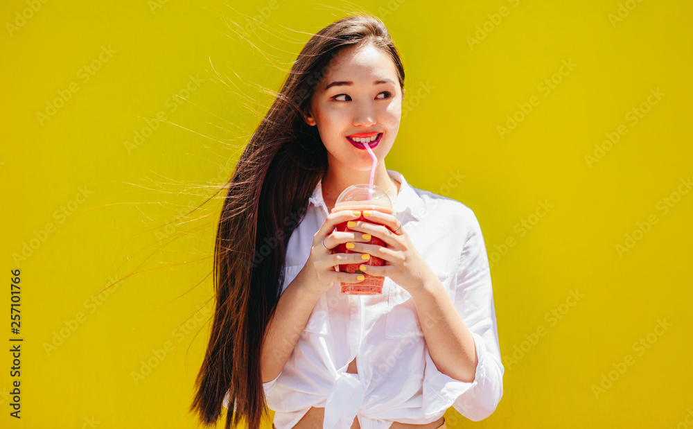 Portrait of smiling woman enjoying a glass of juice