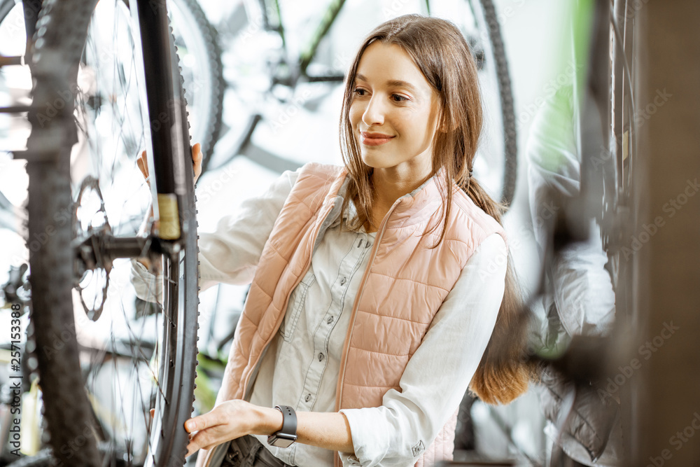 Young and beautiful woman choosing a new bicycle to buy at the bicycle store