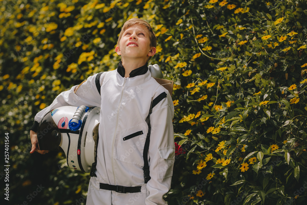 Boy astronaut standing outdoors and looking up