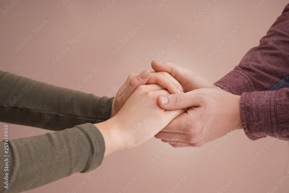 Young couple holding hands together on color background