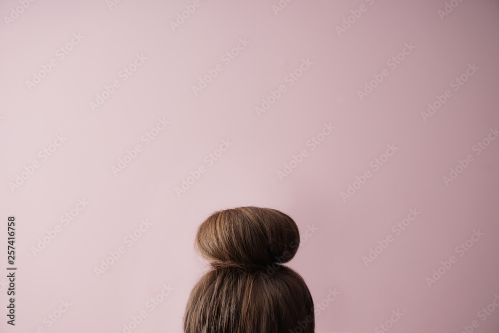 Young woman with hair bun on color background