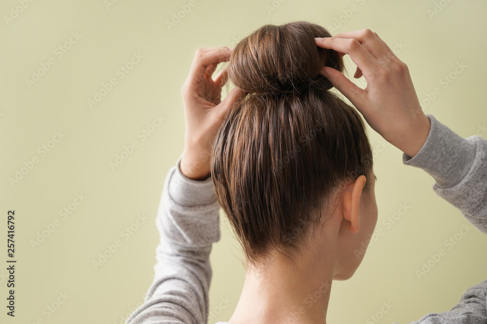 Young woman with hair bun on color background