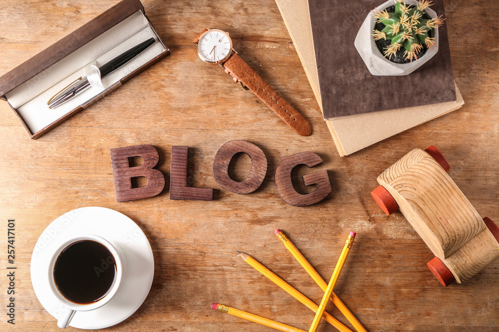 Word BLOG with cup of coffee and stationery on wooden table