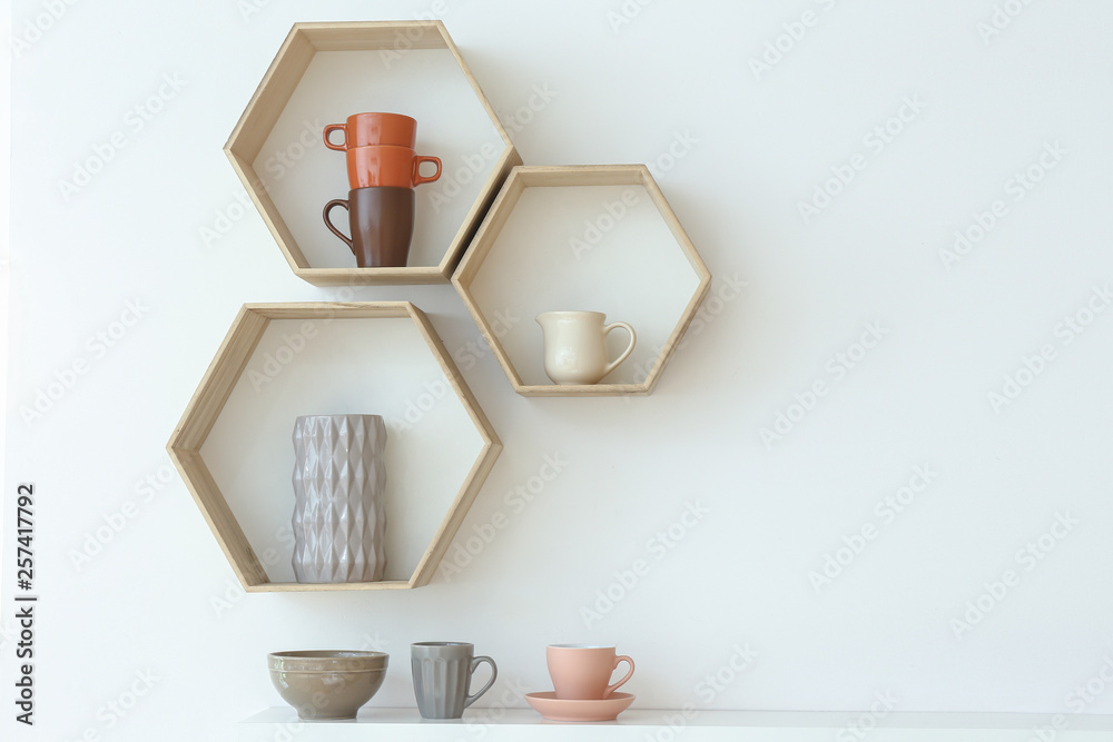 Clean dishes on shelves and table near white wall in kitchen