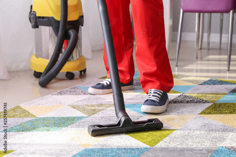 Worker cleaning carpet with hoover