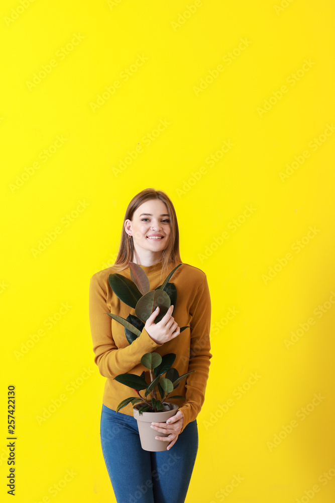 Portrait of beautiful woman with green tropical plant on color background