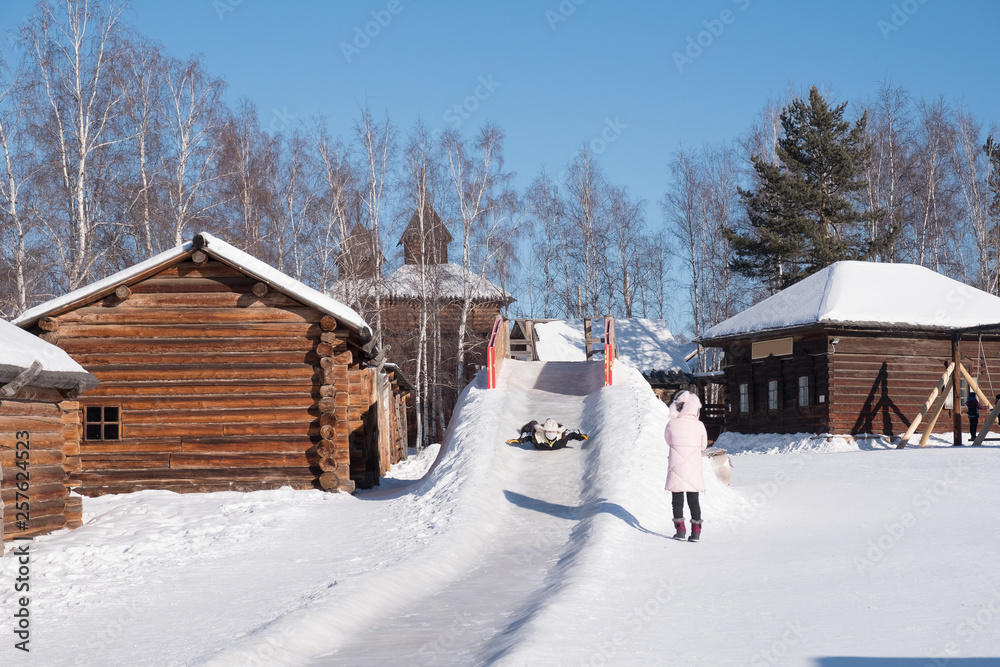 孩子滑下雪地滑梯，家长在旁边观看