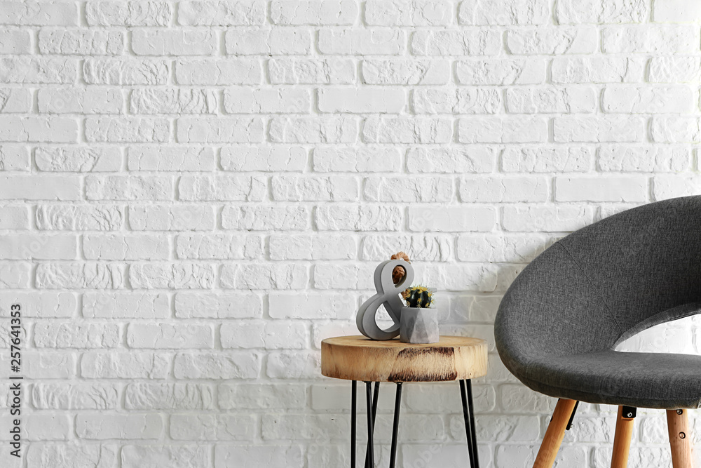 Armchair with table near white brick wall