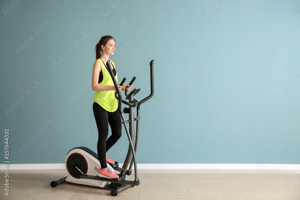 Sporty young woman training on machine in gym