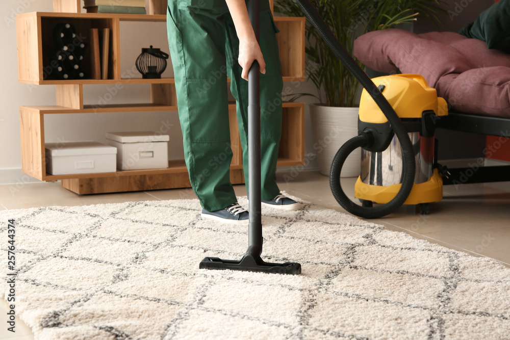 Worker cleaning carpet with hoover