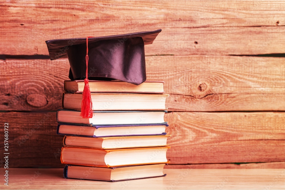 Graduation hat and stacks of books, close-up view