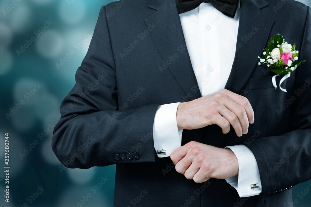 Male groom in wedding suit with bow tie on black