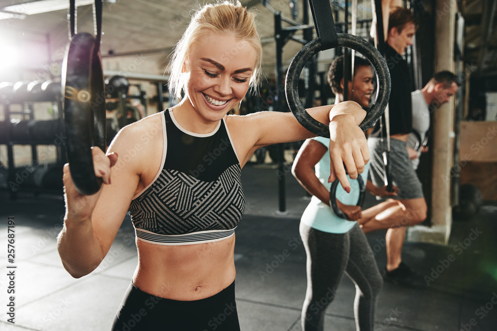 Fit young woman laughing during a gym workout with rings