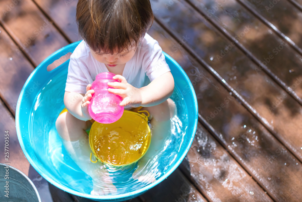 Young toddler boy playing with water outside