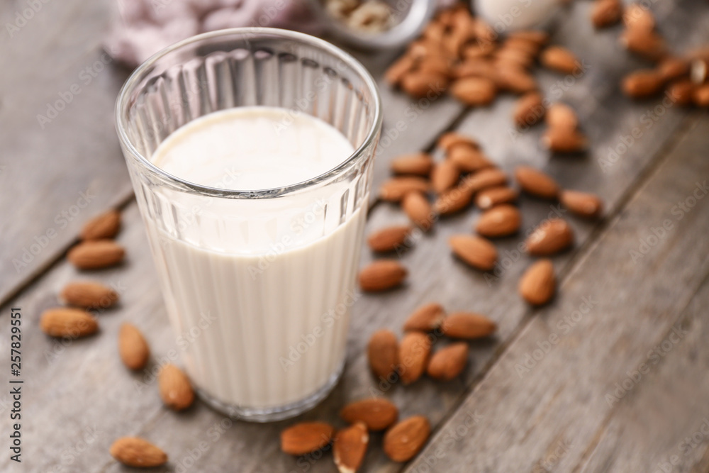 Glass of tasty almond milk on wooden table