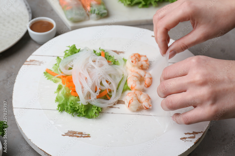 Woman preparing tasty spring rolls