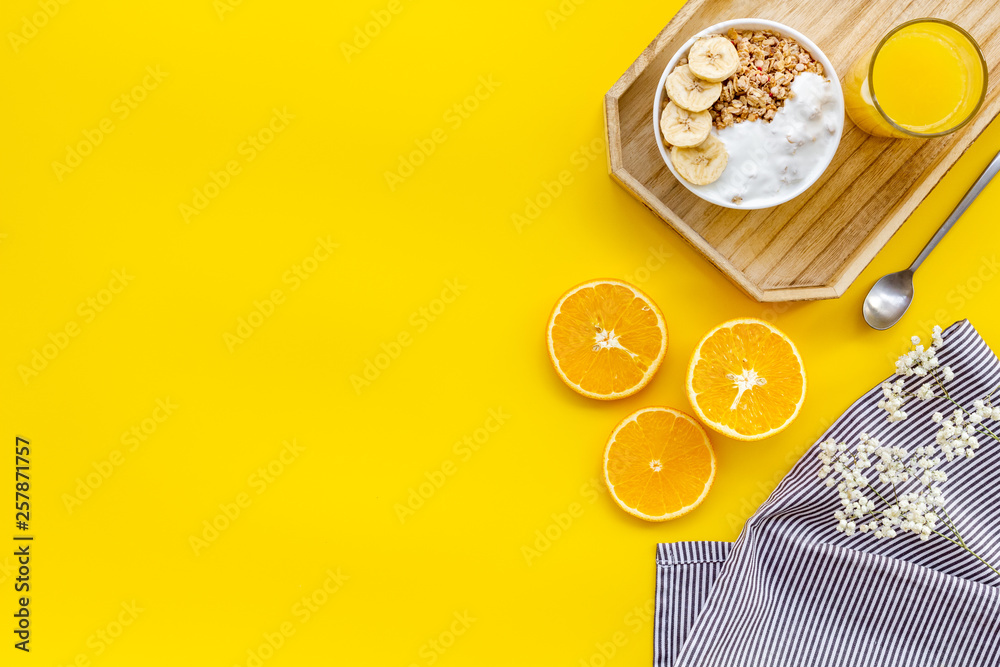 food for healthy breakfast with granola and fresh orange juice on bright yellow background top view 