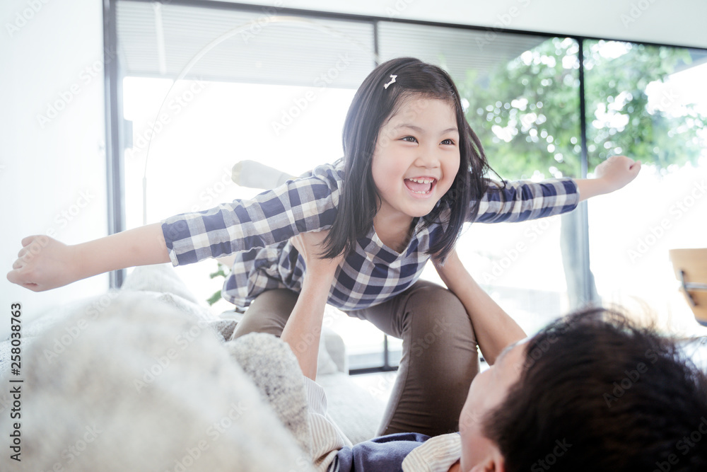 快乐的小女孩女儿和爸爸一起玩，骑爸爸回来，爸爸躺在家里的床上