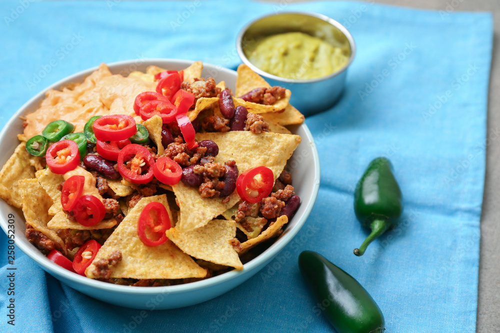 Plate with tasty nachos, minced meat and chili on table