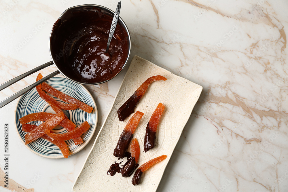 Tasty chocolate covered orange peels on light table