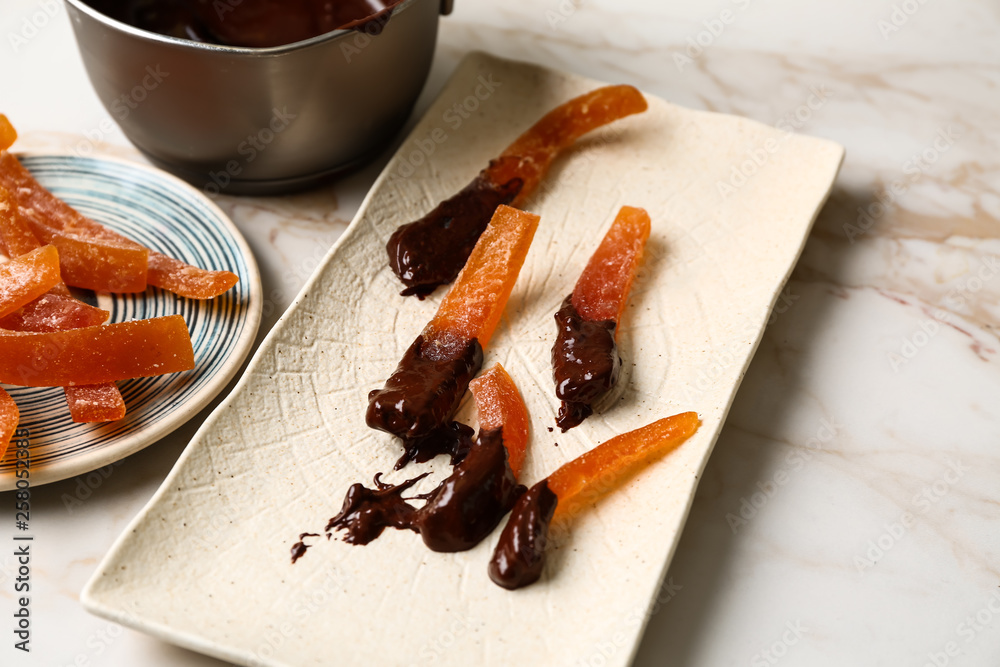 Tasty chocolate covered orange peels on light table