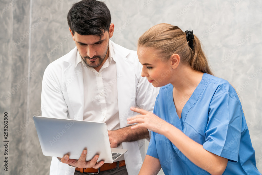 Happy doctor and nurse working with laptop computer in hospital office. Healthcare and medical conce