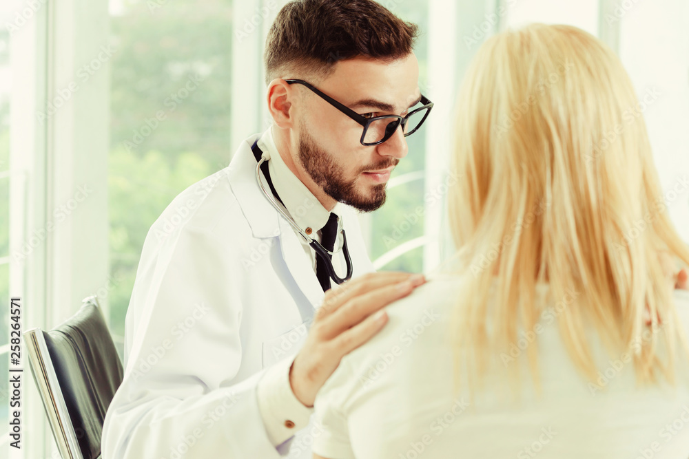 Male doctor is talking with female patient in hospital office. Healthcare and medical service.