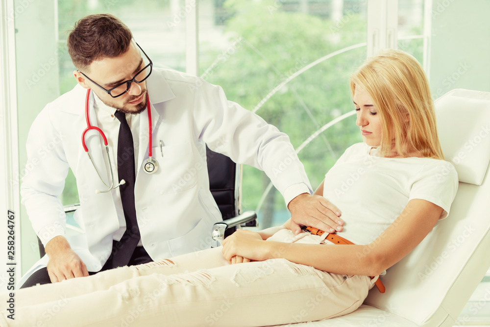 Male doctor is talking and examining female patient in hospital office. Healthcare and medical servi