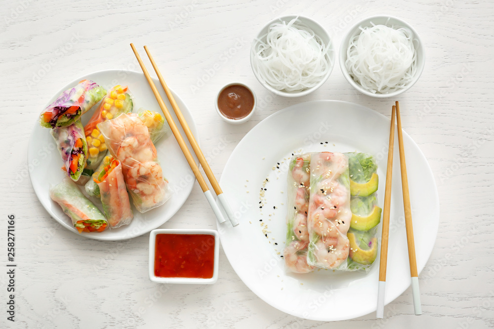 Tasty spring rolls with sauces on table