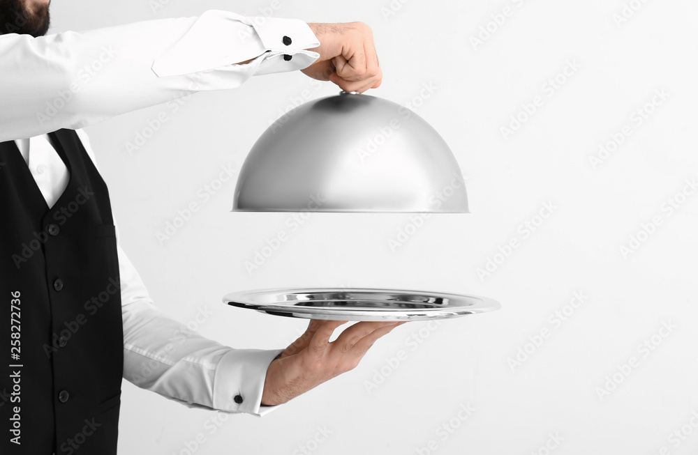 Waiter with tray and cloche on light background