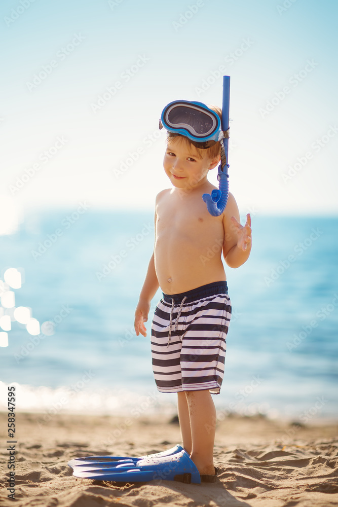 three years old boy playing at the beach with swimming ring