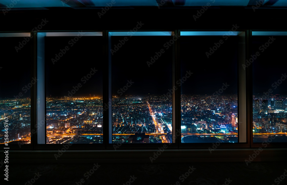 Aerial view of the Osaka skyline at night through a skyscraper window