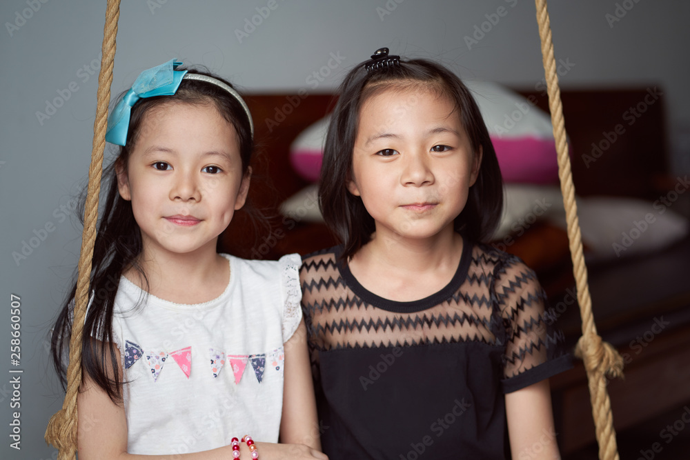 Asian sisters enjoy sit on inhouse swing set