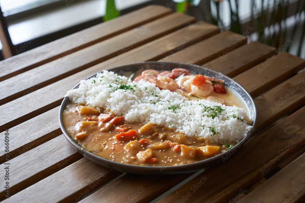 Japanese curry rice with shrimp,meat, carrot and potato on wooden table