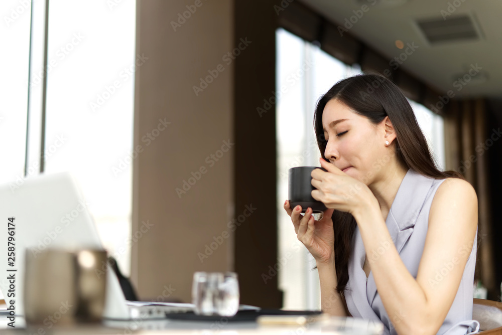 亚洲聪明漂亮的女孩坐在咖啡馆喝咖啡休息。她关门了