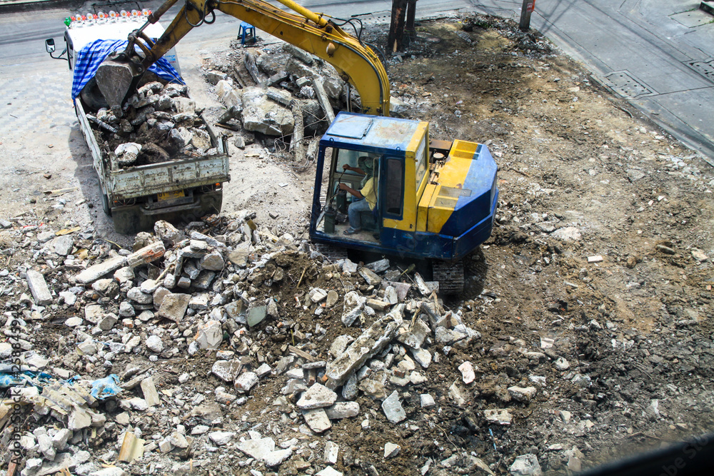 Backhoe excavator and truck clearing wreckage, demolish or remove a building.