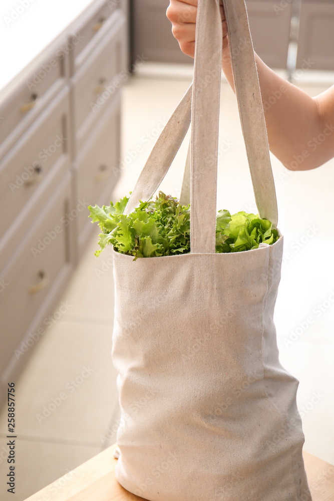 Young woman with fresh vegetables in eco bag indoors